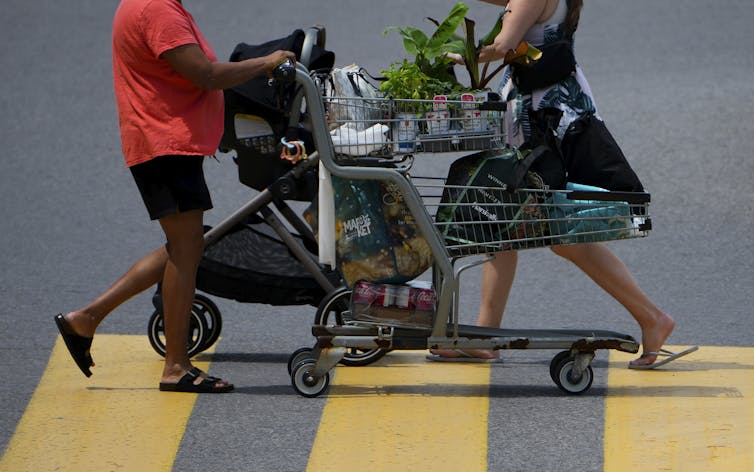 Gente vista desde la puerta hacia abajo empujar carros de compras sobre peatones