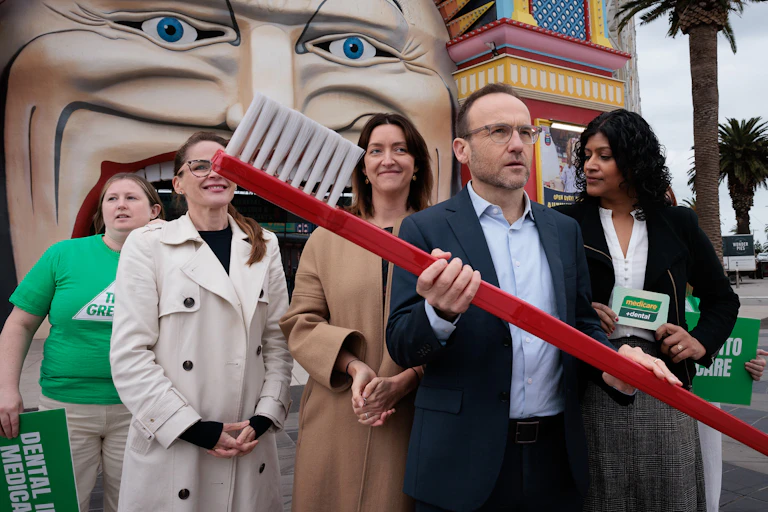 man holds giant toothbrush with group of women