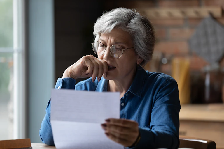 Woman sitting at table contemplating a letter she is holding