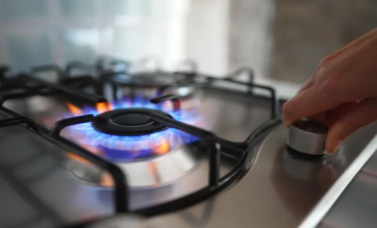 hand turning on gas stove.