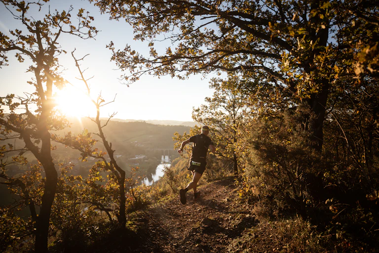 Photographie d'un homme de dos courant dans la forêt.