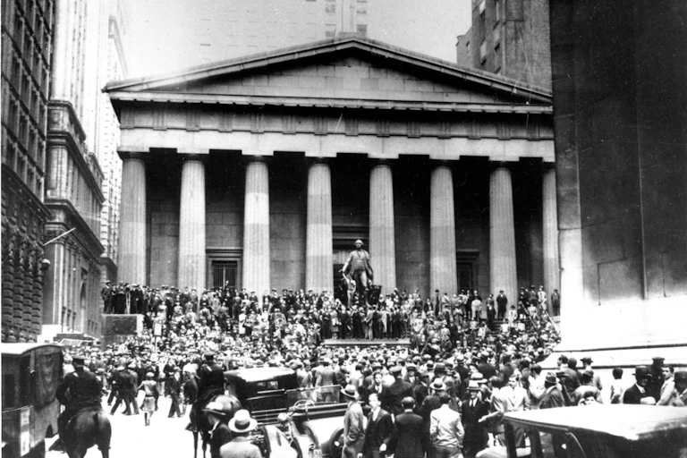 une photo en noir et blanc : au fond on voit le bâtiment de la bourse de New York et des personnes en grand nomrbe qui s'en approchent