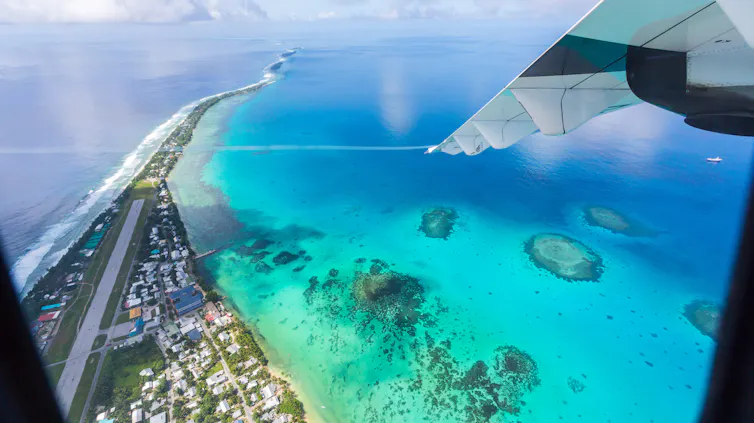 Tuvalu under the wing of the airplane. Aerial view of Funafuti atoll and airstrip of international airport in Vaiaku from air. Fongafale motu. Island nation in Polynesia, South Pacific Ocean, Oceania