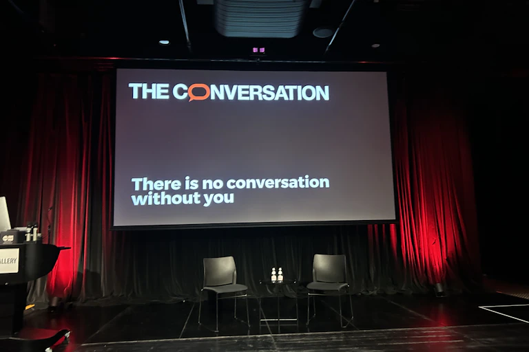 A photograph of a digital display of The Conversation logo along with the words There is no conversation without you