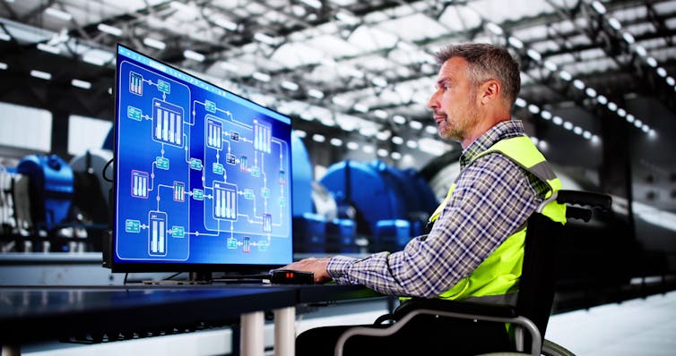 older worker in hi-vis jacket using a computer.