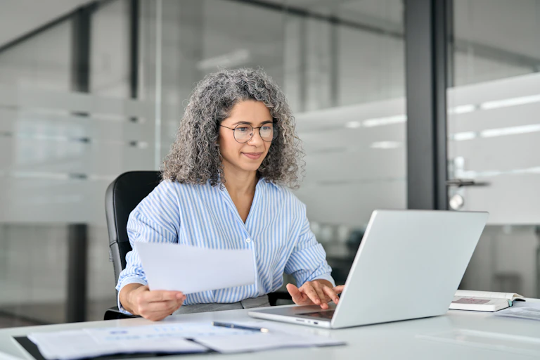 middle-aged female worker sitting at a laptop in an office.