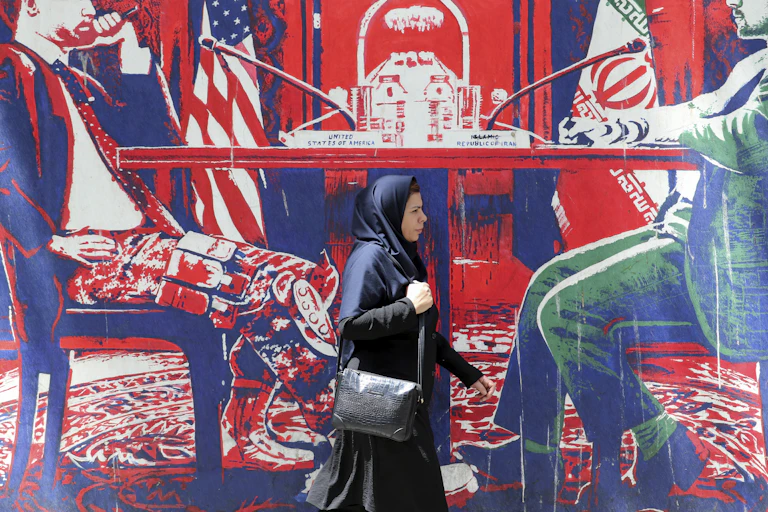 A woman walks outside the former US embassy in Tehran which is decorated with murals showing US and Iran in negotiations.