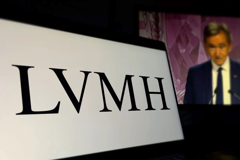 un logo LVMH et Beranrd Arnault (flou) sur un écran. l'image est vraissemblablement issue d'une réunion des actionnaires