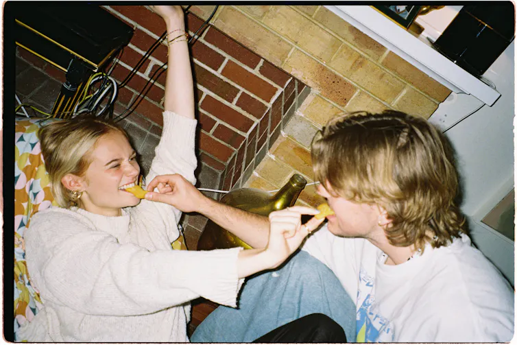 Girl and boy feeding each other crisps