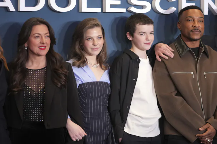 Four people posed against a blue backdrop.