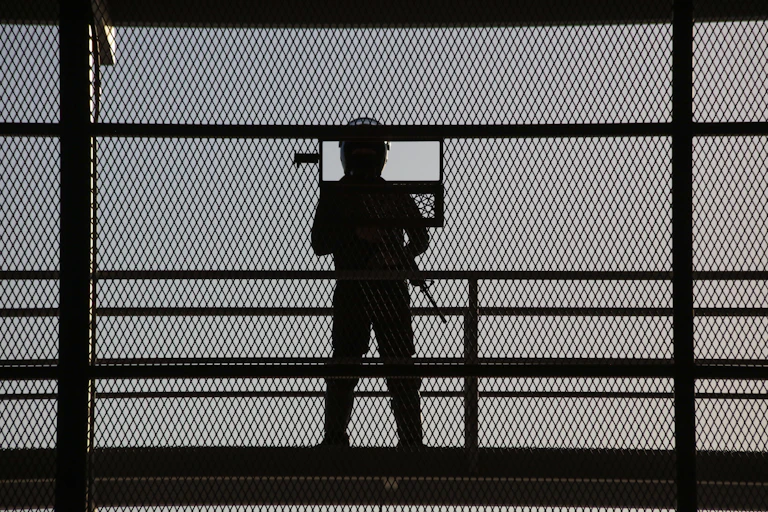 A guard with a gun at a prison gate.