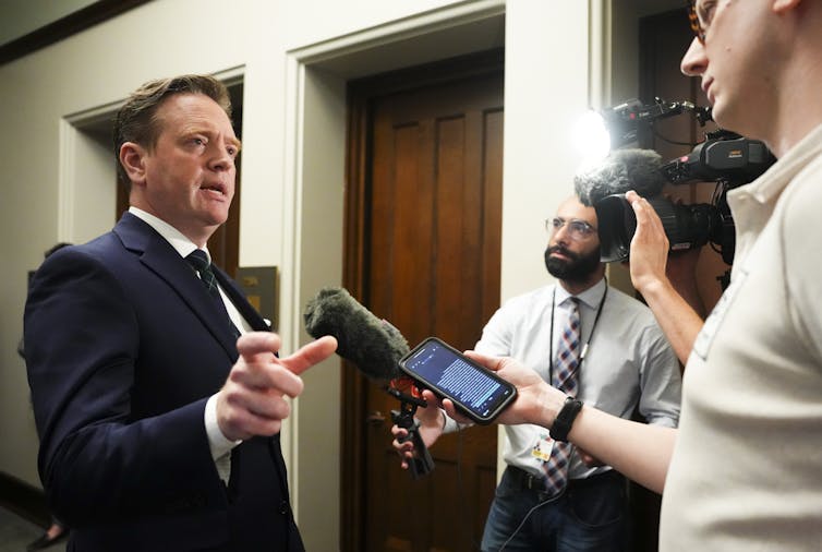 El hombre hace un gesto a los periodistas.