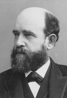 Black and white photo of a bearded, balding man in a suit