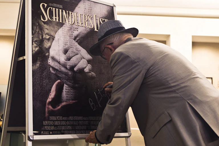 A man in grey suit and had signs a poster.
