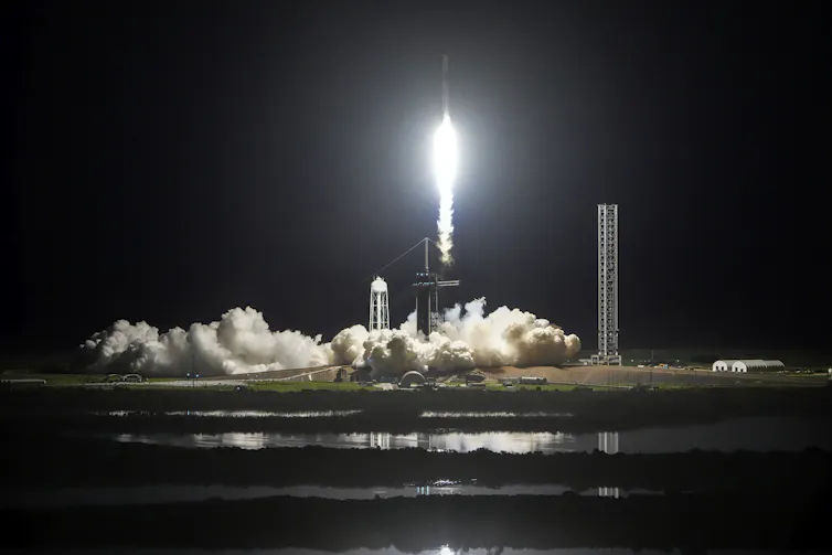 A rocket launching into a dark sky, leaving behind a cloud of smoke.