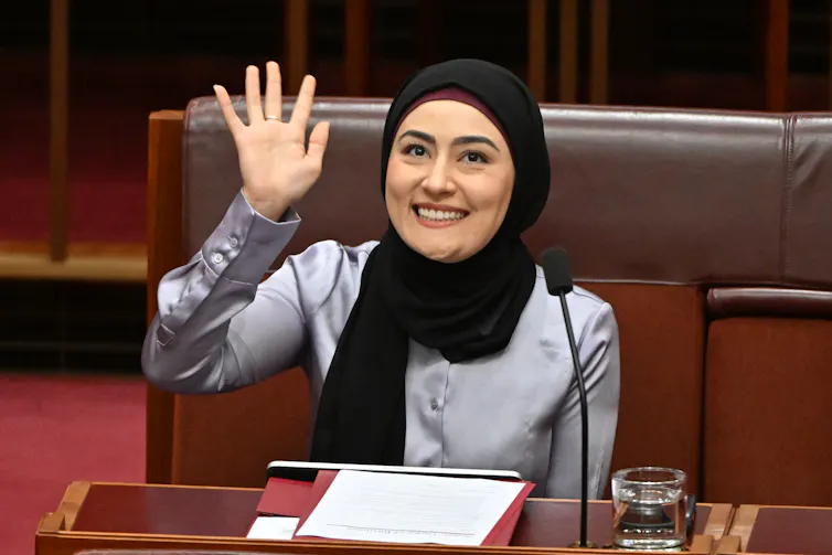 Senator Fatima Payman, wearing a black hijab, smiling and waving in the Senate