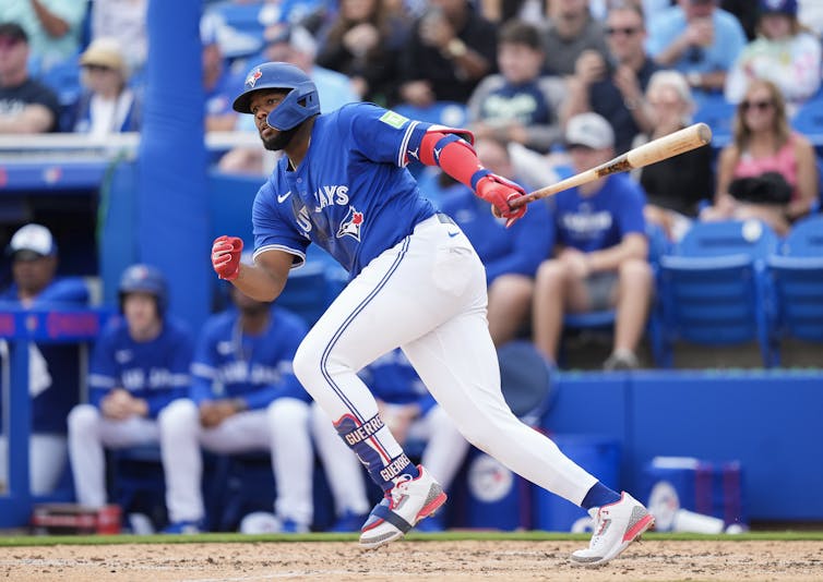 El hombre en una camiseta azul trabaja por bate de béisbol con un bate en la mano izquierda