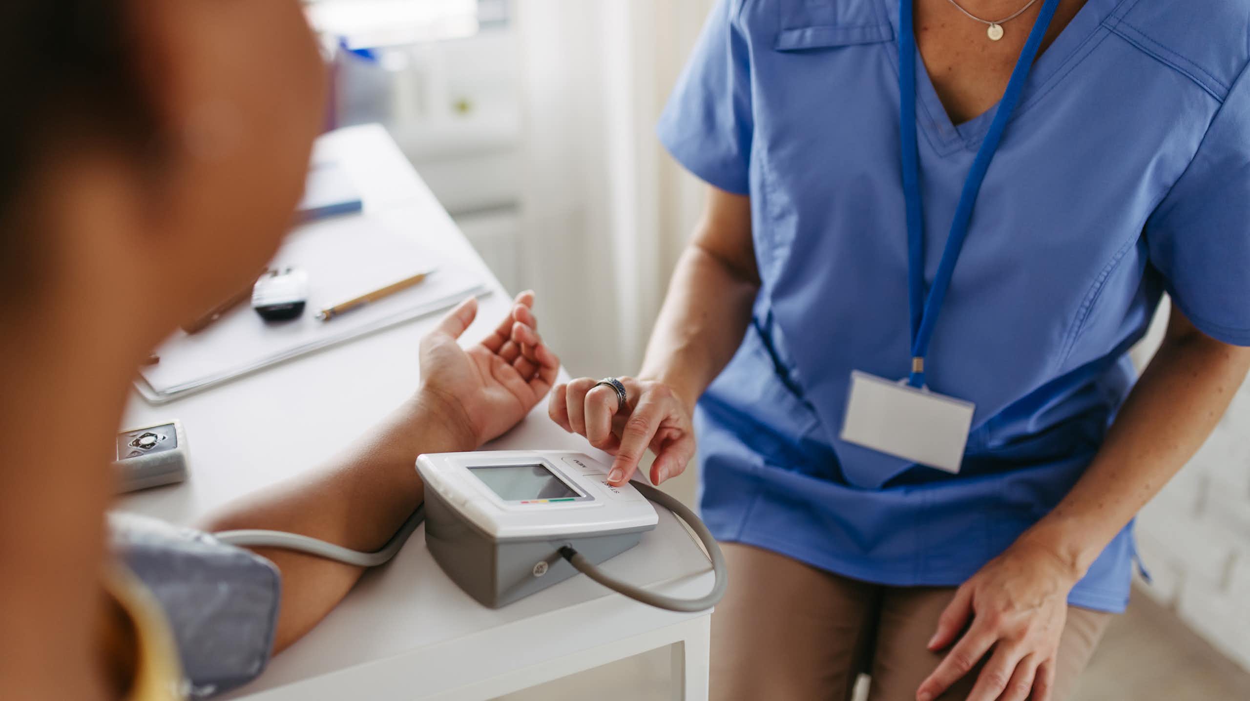 Over-the-shoulder shot of patient having blood pressure measured by a clinician
