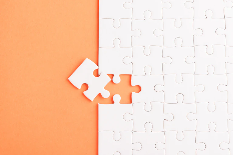 Top view of plain white jigsaw puzzle shot on an orange background