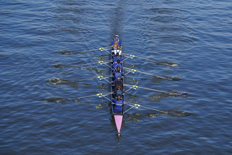 Oxford university rowing women's eights crew practice in the morning sunshine on the river Thames.