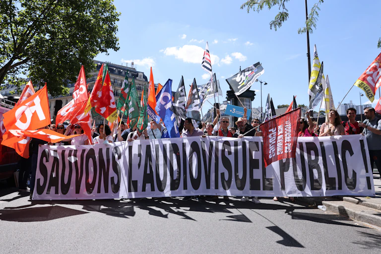 Des travailleurs des médias publics français crient des slogans alors qu'ils marchent derrière une banderole traduite par « Sauvons les médias publics » lors d'un rassemblement organisé par les syndicats à Paris le 28 juin 2022, pour protester contre l'intention du gouvernement de mettre fin à la redevance télévisuelle. (Photo par Thomas COEX / AFP)