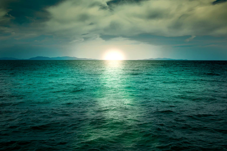um pôs do Sol sobre um oceano esverdeado