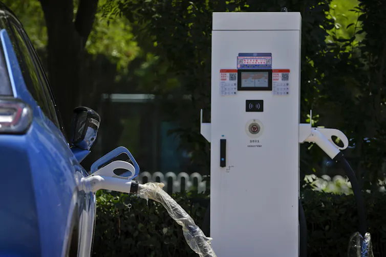 An electric vehicle charges at an electric vehicle charging station
