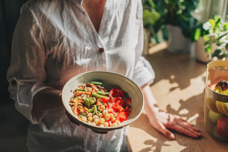 A woman holds a bowl of healthy food.