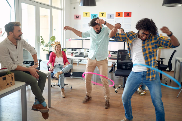 Dans un décor coloré de bureaux, des personnes font du hula hop.