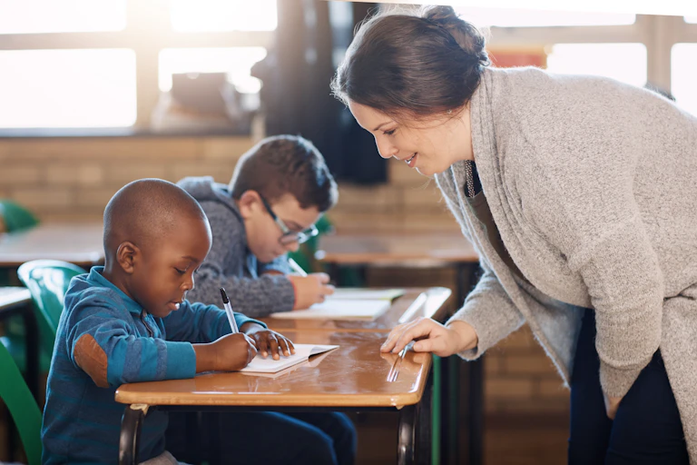 Profesora en clase con dos alumnos pequeños.