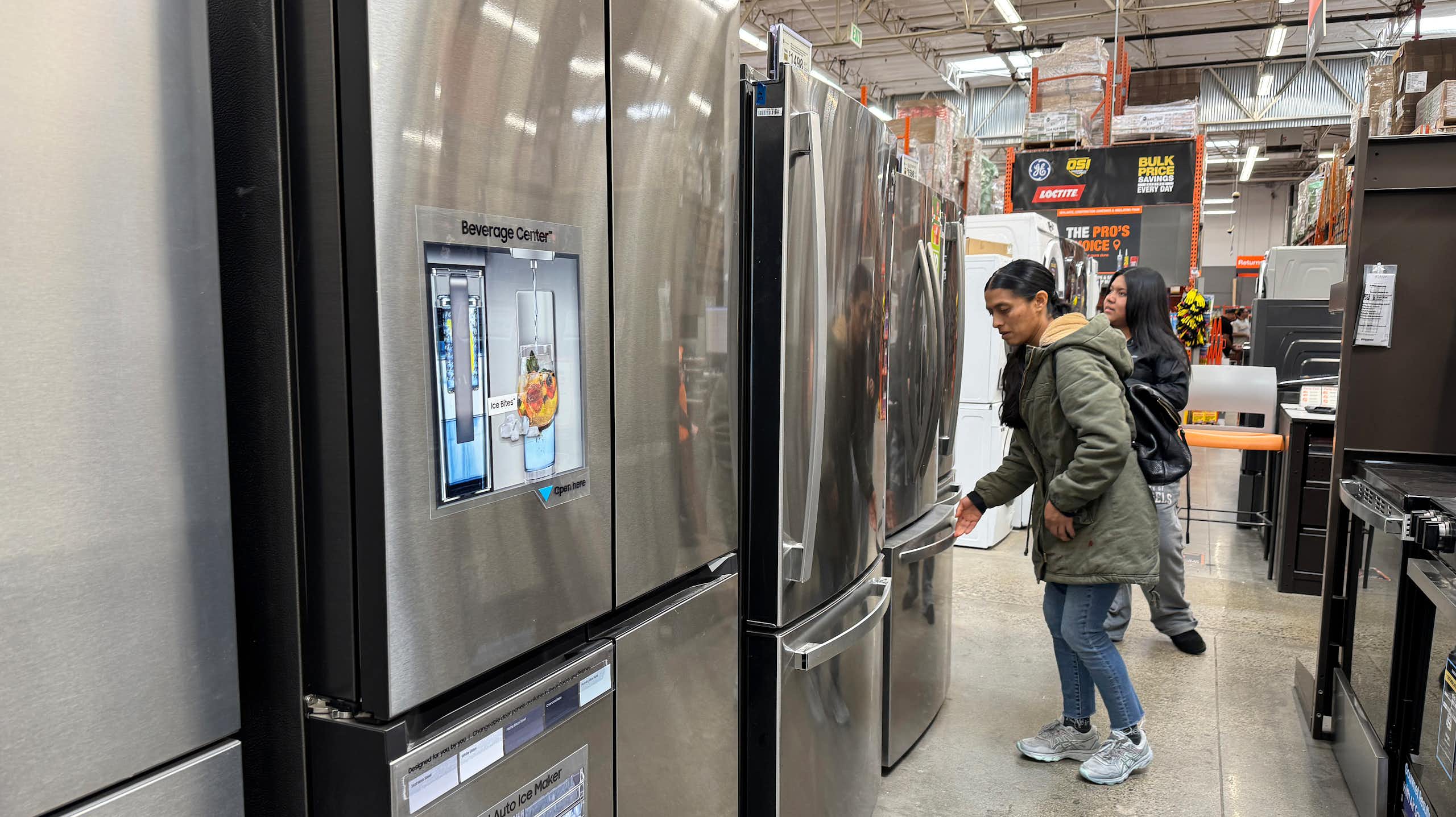 People stand in an aisle lined with refrigerators.