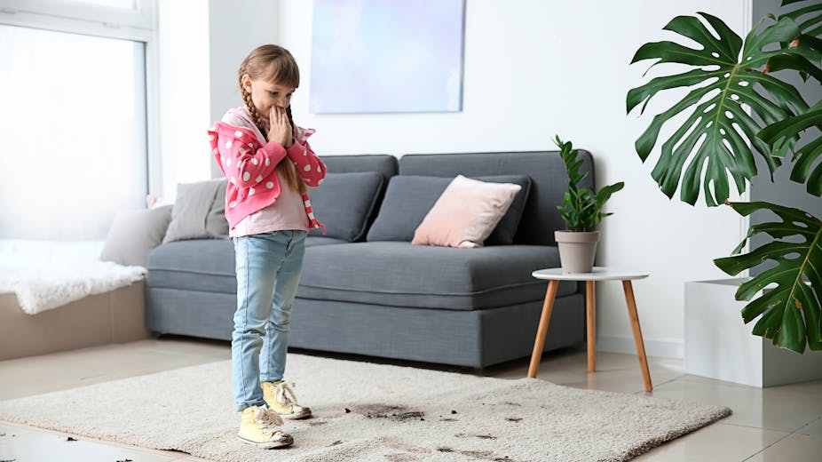 Little girl worried after trekking dirty footprints over a cream coloured rug
