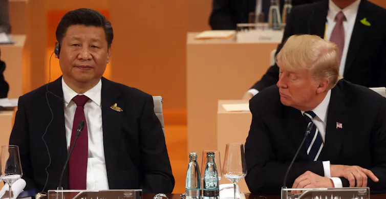 Two men sit side by side at a conference.