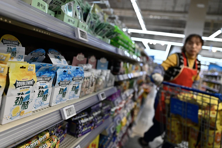 A woman pushes a cart down an aisle in a Beijing grocery store.