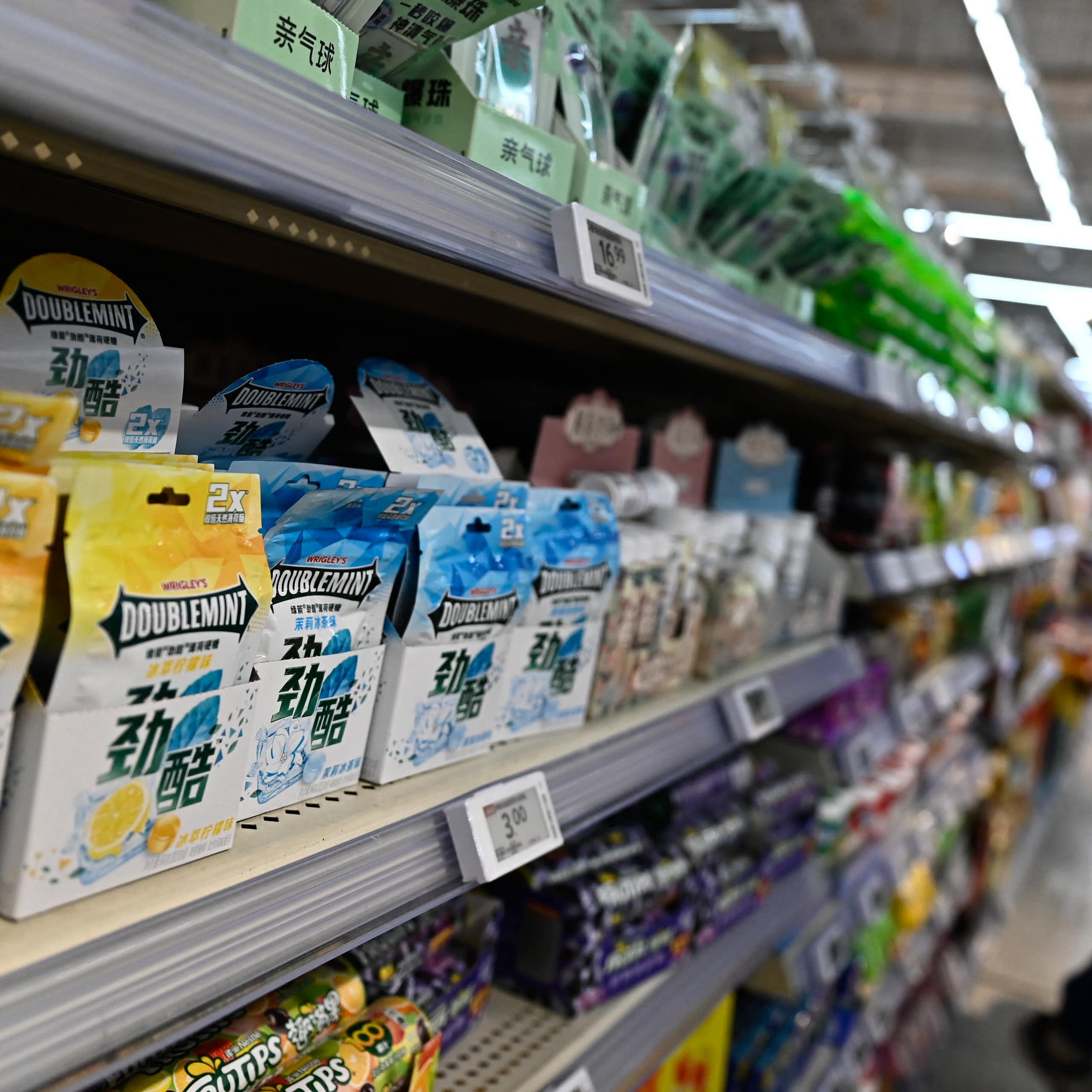 A woman pushes a cart down an aisle in a Beijing grocery store.