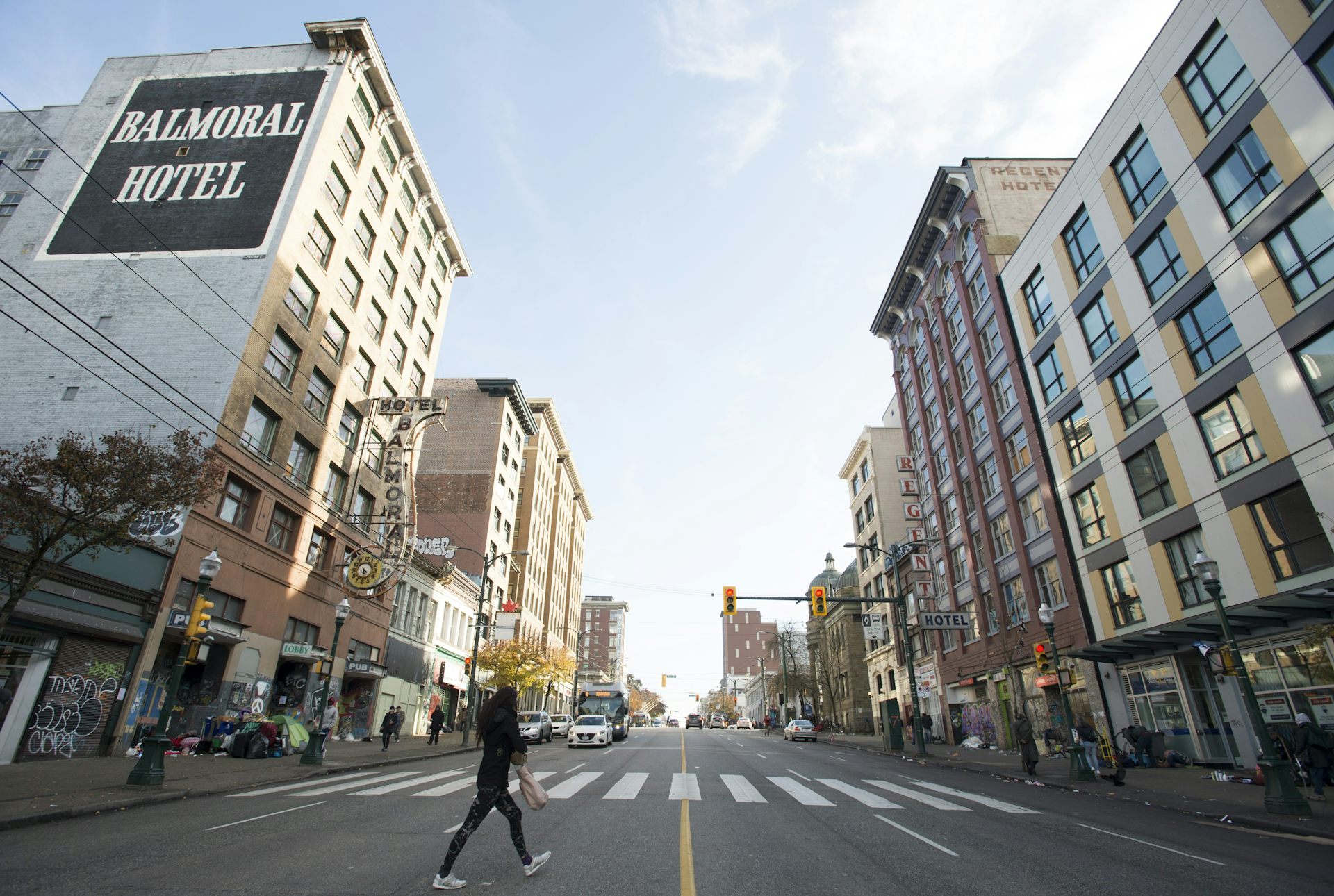 A photo of a long two-way street in a city with multi-floor buildings on either side 