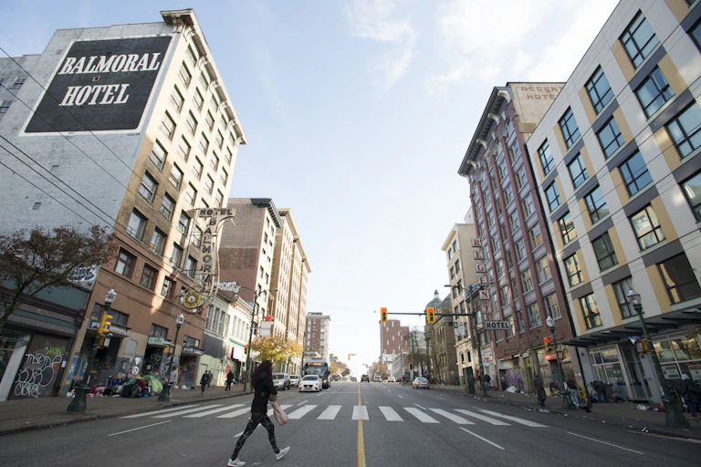 A photo of a long two-way street in a city with multi-floor buildings on either side