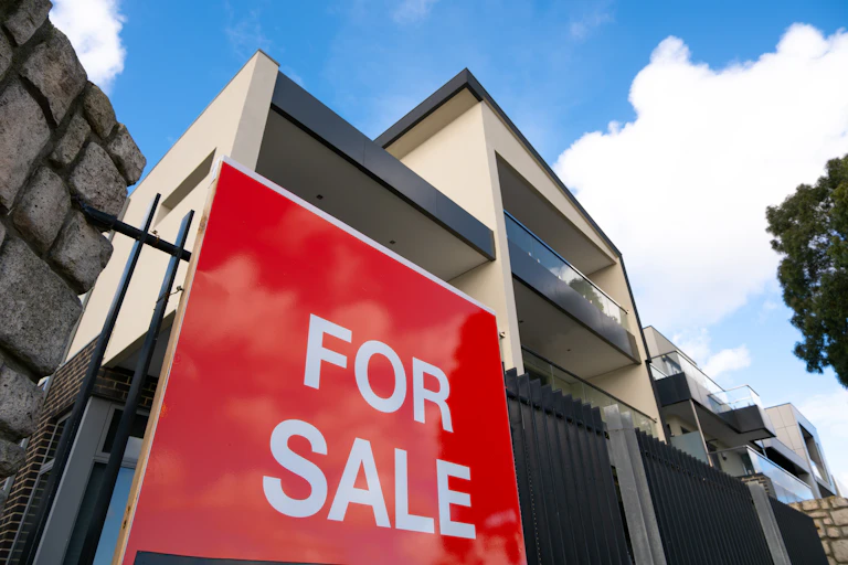 Block of apartments with a red for sale sign out the front