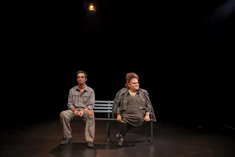 Production image: a man and a woman sit on a bench.