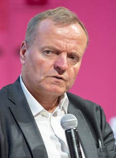 A man wearing a suit speaking into a microphone.