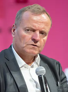 A man wearing a suit speaking into a microphone.