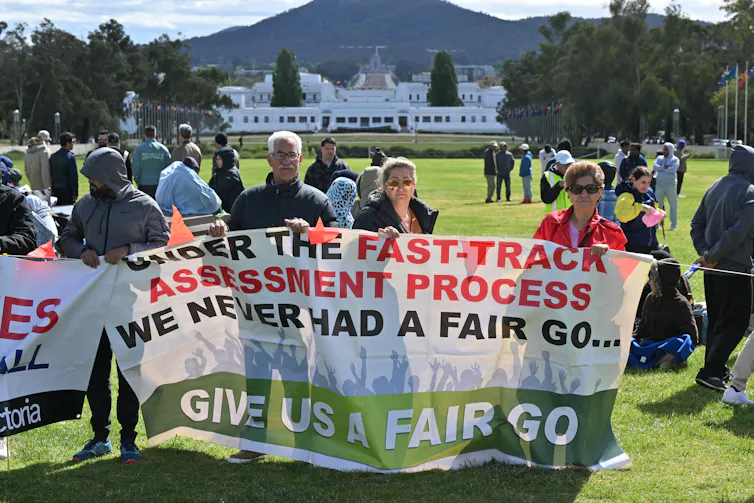 Protesters hold signs during a rally for refugee rights outside Parliament House in Canberra, Tuesday, October 17, 2023