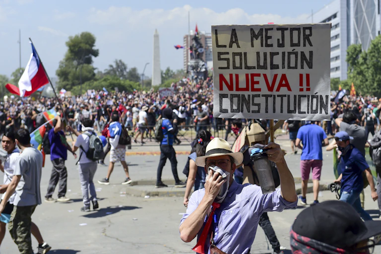 Un homme tient une pancarte sur laquelle on peut lire « Une nouvelle constitution, la meilleure solution » lors d'une manifestation à Santiago du Chili le 24 octobre 2019.