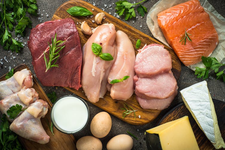 A collection of animal proteins on a chopping board, including beef chicken and fish.