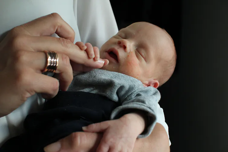 A photo of a person cradling a newborn baby.