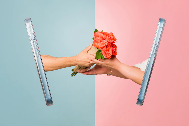 Conceptual image showing two phones with hands reaching out to pass flowers between them.