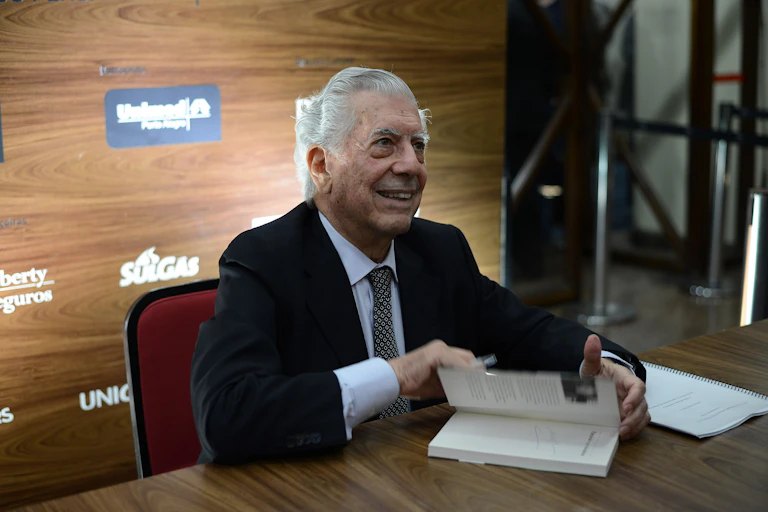 Un hombre sonríe mientras abre un libro.