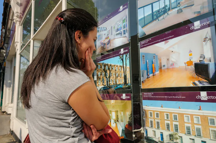 young woman looking in the window of an estate agent.