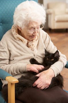 Senior woman relaxing in a chair holding a fluffy black cat.
