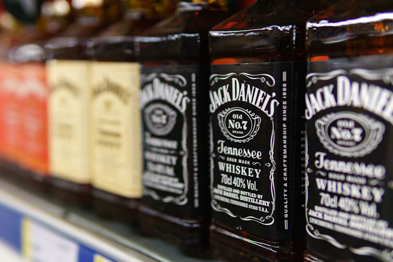 bottles of jack daniels lined up on a supermarket shelf.